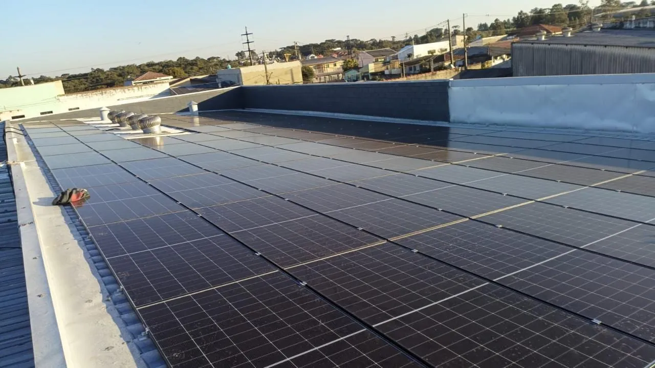 Painéis solares alinhados ao longo do telhado metálico de um galpão