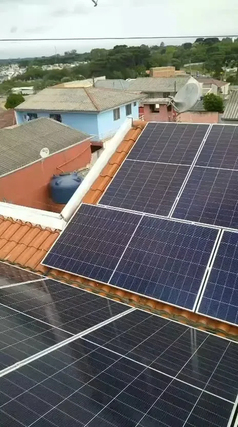 Painéis solares em telhado de telhas cerâmicas, com vista para a vizinhança